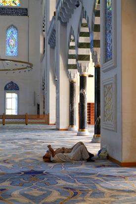 Das Bild zeigt zwei Frauen, die auf dem Boden einer Moschee liegen und an die Decke schauen.